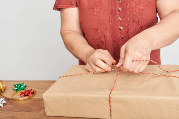 istock Hands of an unknown mature woman tying a Christmas gift with a decorative string 1431983337