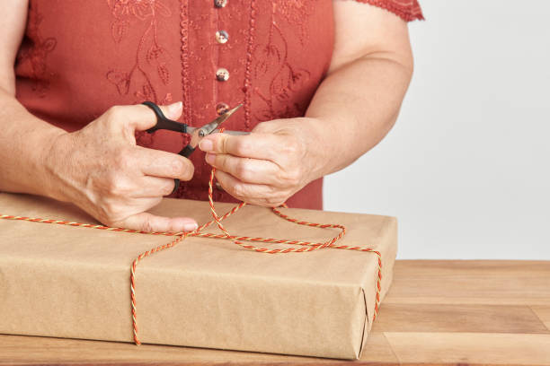 istock Unknown woman cutting a cord, tying a Christmas gift with a decorative string 1431983510