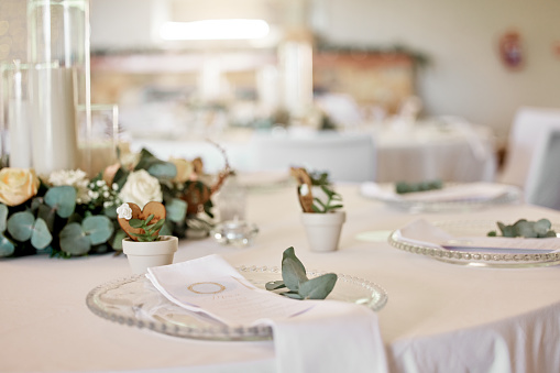Wedding, dinner table and decoration at a reception party for luxury fine dining at banquet. Natural decor, plates and tableware at a rustic marriage celebration event in a empty elegant room or hall
