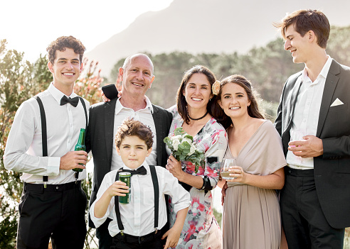 Happy, portrait and family at a wedding to support happiness, love and the marriage together. Old man, sister and brothers of the groom with mother holding a bouquet of flowers at an event outdoors