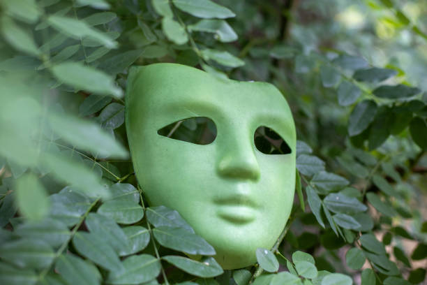 green carnival mask hidden in tree leaves