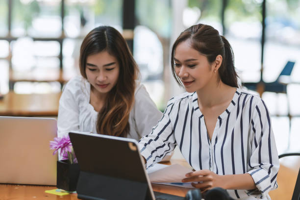 istock Two young Asian businesswoman working together using documents at the office. 1431987803