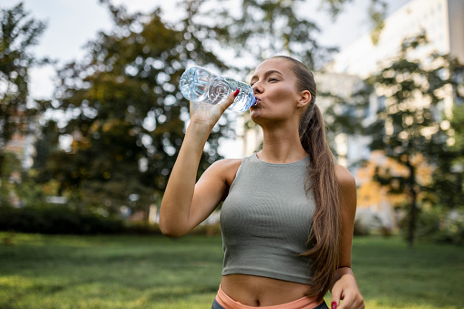 Fit sporty woman drinking water after intensive workout