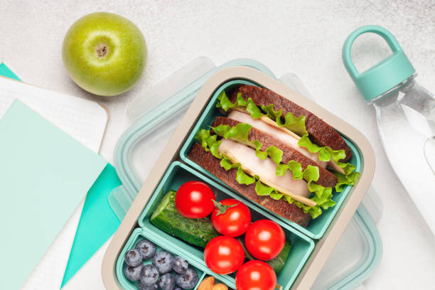 istock School lunch box. Ham and cheese sandwich, vegetables, nuts and berries in a plastic container. Top view. Back to school concept. 1431988590