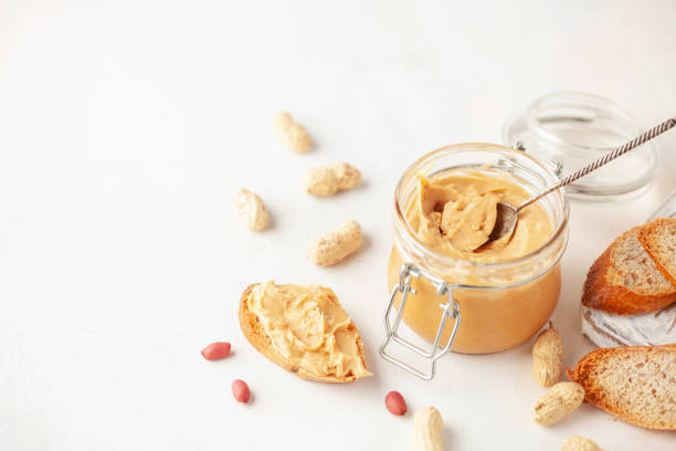 istock Peanut butter or paste jar and heap of nuts on light background. 1431988680
