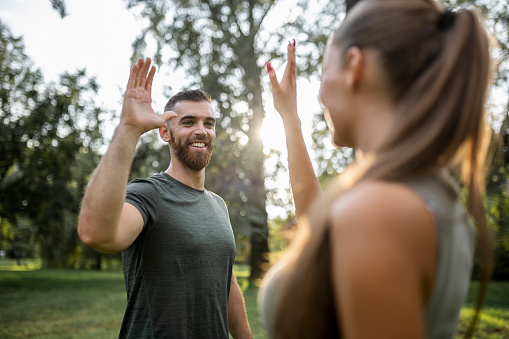 Two athletic people greeting each other with high five gesture during jogging workout
