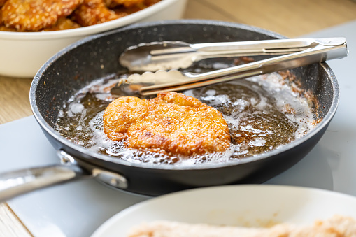Pan full of oil is used for frying breaded meat while making wiener schnitzels.