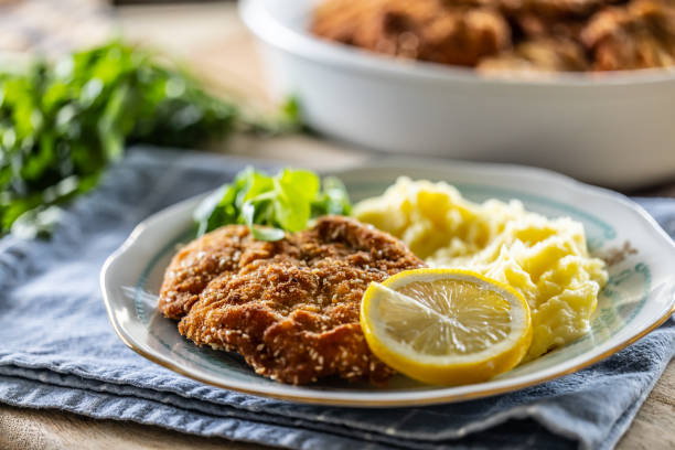 パン粉を塗った肉にポテトマッシュ、レモンと野菜のスライスを添えて。 - viennese schnitzel ストックフォトと画像