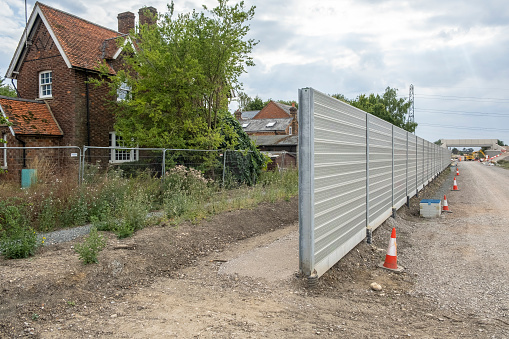 Winslow, UK - July 29, 2022. Rail noise barrier protecting houses at Verney Junction. Construction of the new railway line East West Rail between Oxford and Bedford