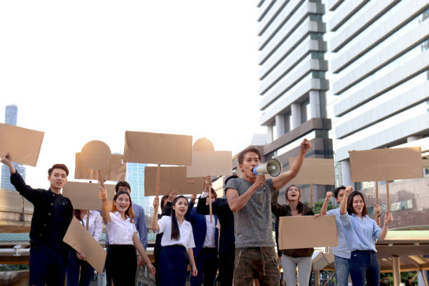 istock Crowds of discontented people hold blank banners placards protesting at city, leader shouts through megaphone with men and women group rebellions doing protest, protesters at political rally parade 1431995985