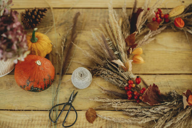 istock Stylish autumn wreath on rustic table flat lay. Rustic autumn wreath with dried grass, berries, herbs on wooden table with pumpkins and scissors. Fall decor and arrangement in farmhouse. 1431998241