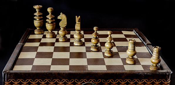 Old leather chess board with wooden chess in perspective.