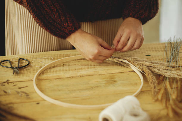 istock Making stylish autumn wreath on rustic table. Hands arranging dried grass on hoop on wooden table with scissors, thread. Fall decor and arrangement in farmhouse. 1431999203