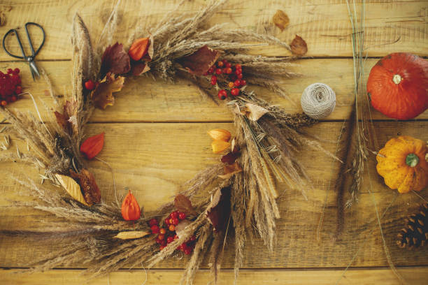 istock Stylish autumn wreath on rustic table flat lay. Rustic autumn wreath with dried grass, berries, herbs on wooden table with candle, scissors and pumpkins. Fall decor and arrangement in farmhouse. 1431999351