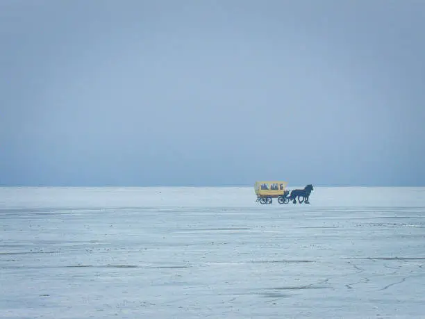 I saw this horse-drawn carriage on the beach of Borkum in winter. She drove back to the village from the extreme northwest end. Because of the cold, the canopy of the carriage was closed. The beach was covered with fine snow. The lonely carriage and yellow form a good contrast to the blueish emptiness of the beach.