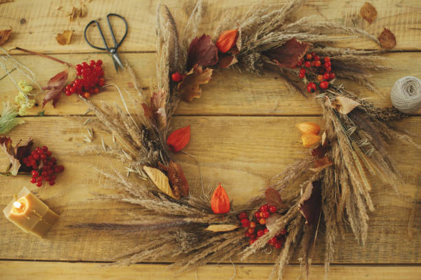 istock Stylish autumn wreath on rustic table flat lay. Rustic autumn wreath with dried grass, berries, herbs on wooden table with candle, scissors, thread. Fall decor and arrangement in farmhouse. 1431999546