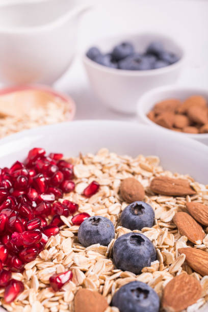 bowl with rolled oats, blueberries, pomegranate seeds and almonds in the foreground with selective focus