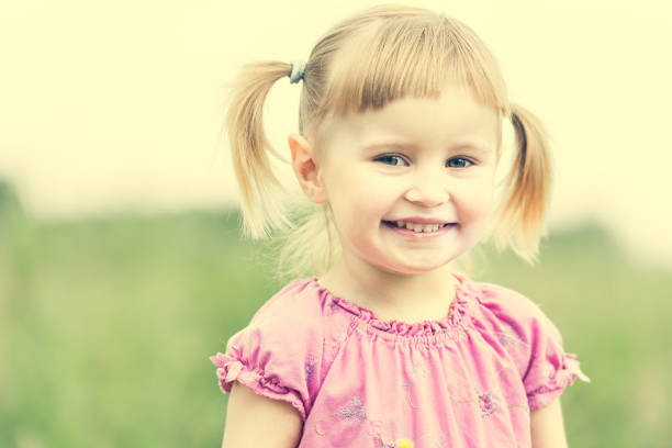 Cute little girl on the meadow in summer day close-up