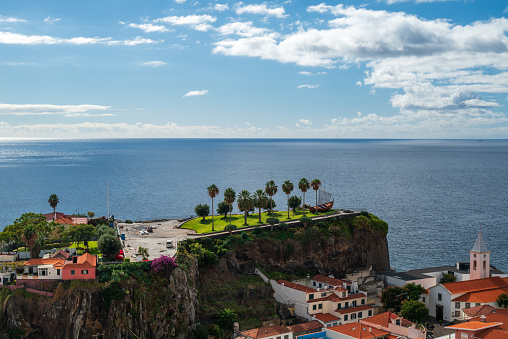 View of the small community of camara de lobos on Madeira Portugal with a blue sky and the horizon in the background.