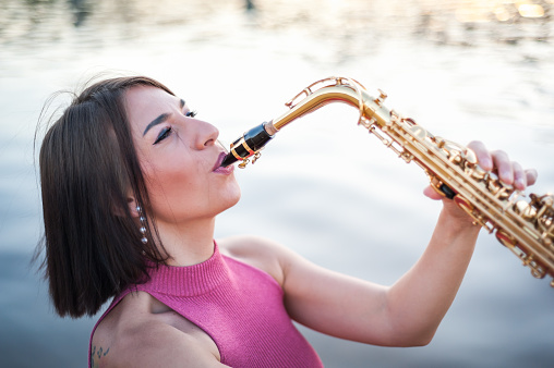 Woman playing the saxophone at sunset