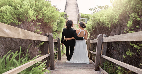 Wedding, love and back of couple in garden walking after destination ceremony in South Africa. Nature, bride and groom walk on outdoor park. Man and woman going down path of stairs after marriage.