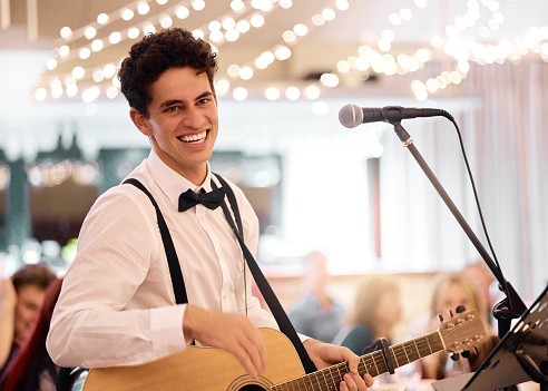 Guitar man, wedding and live music performance by jazz singer, happy artist and acoustic band. Young musician signing, playing instrument and entertainment at marriage ceremony, party and celebration