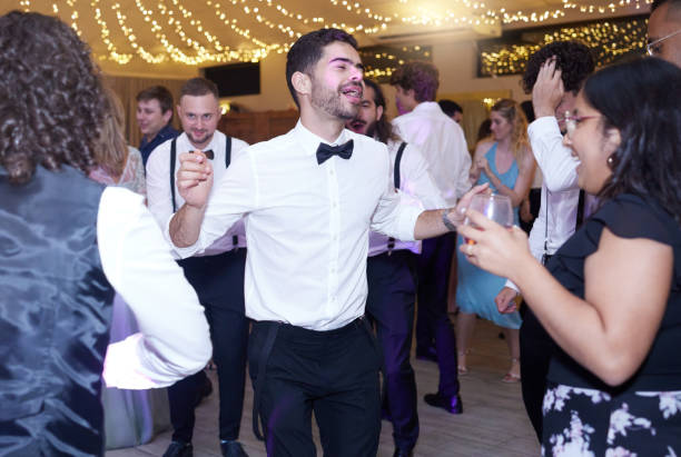 drunk wedding group dancing to music on the dance floor of the celebration reception or event. guests and people having fun while singing and drinking with a song at a marriage disco after party. - celebration drunk drinking after party imagens e fotografias de stock