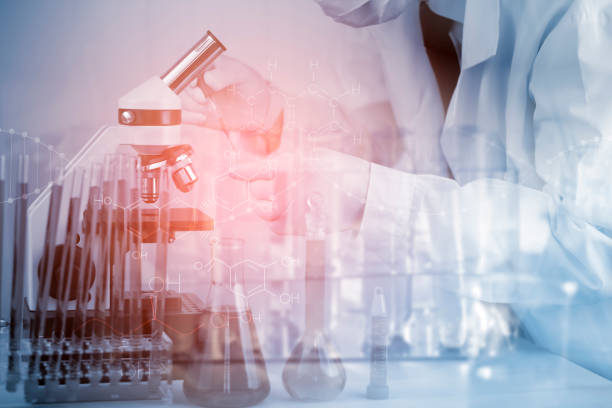 istock biochemical research scientist working with a microscope for the virus,Doctor man write a history of the experimental results in a , laboratory glassware containing chemical liquid for design. 1432006824