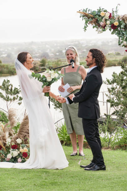 istock Wedding, speech and couple laughing at ceremony service with mc talking in to microphone for celebration, event and party. Marriage, lifestyle and happy bride and groom at countryside park venue 1432006837