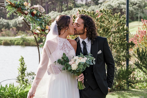 Wedding, couple or kiss with a bride and groom kissing on their marriage day after a ceremony or celebration event at an outdoor venue. Love, romance and tradition with a husband and wife outside