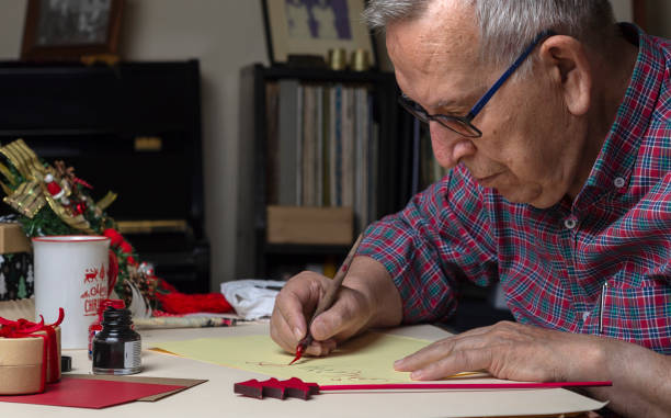 年配の男性がペンとインクでクリスマスカードを書く。手書き書道 - inoki antonio ストックフォトと画像