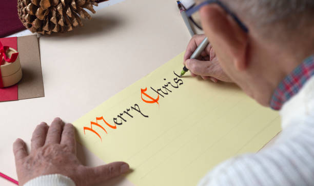 年配の男性がペンとインクとゴシック様式でクリスマスカードを書きます。手書き書道 - inoki antonio ストックフォトと画像