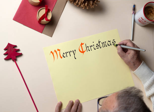 ゴシック様式の手書きでクリスマスの挨拶状を書く老人の手の上面図 - inoki antonio ストックフォトと画像