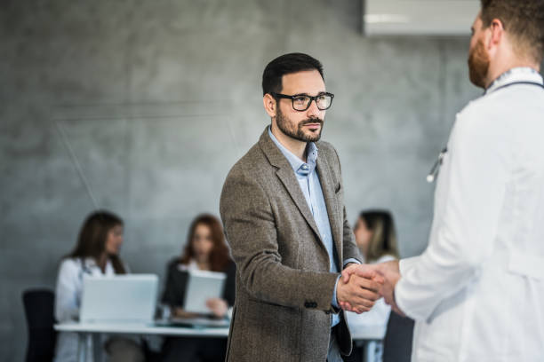 istock Businessman and doctor shaking hands in doctor's office. 1432010651