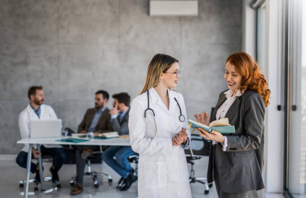 Businesswoman talking with female healthcare worker in doctor's office. stock photo