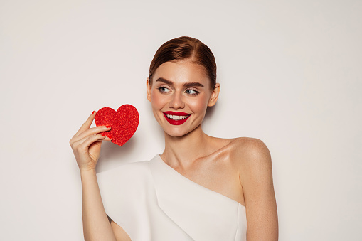 Beautiful emotional woman holding artificial heart