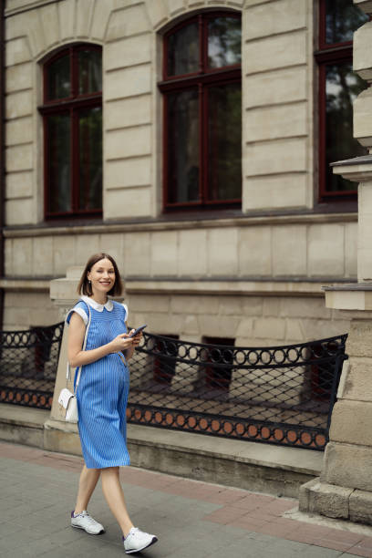 istock Pregnant woman walking through the city using a smartphone 1432019098