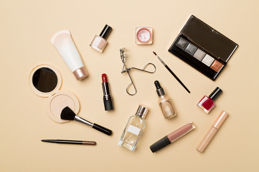 Different makeup products on color background, top view.