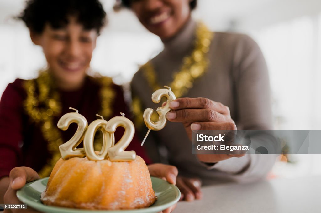Close up of Mother and son celebrating Ney Year  and eating Christmas cake with golden candles shaped 2023 numerals 2023 Stock Photo