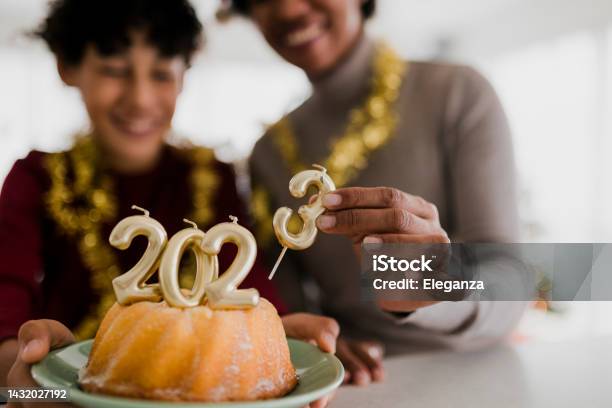 Close Up Of Mother And Son Celebrating Ney Year And Eating Christmas Cake With Golden Candles Shaped 2023 Numerals Stock Photo - Download Image Now