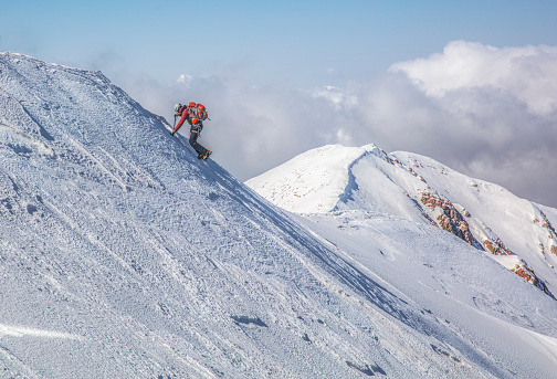 man climbing to the top of a snowy mountain