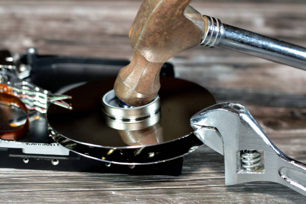 istock Spanner wrench and steel hammer with HDD platters, hard disk drive disassembled damaged components, computer maintenance, recovery, data erase, data killer software concept 1432032866