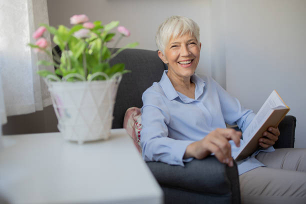 istock Happy woman reading book at home 1432034410