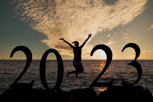 Silhouette of a woman jumping in 2023 on the hill at sunrise stock photo