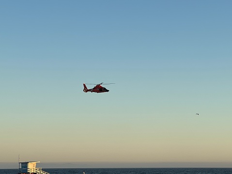 Coast Guard helicopter flying over Venice Beach in the sunset. Venice, California, USA