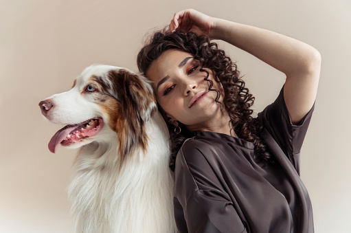 Beautiful woman and her dog posing together, Australian Shepherd Dog and young Curly woman, pets and leisure concept
