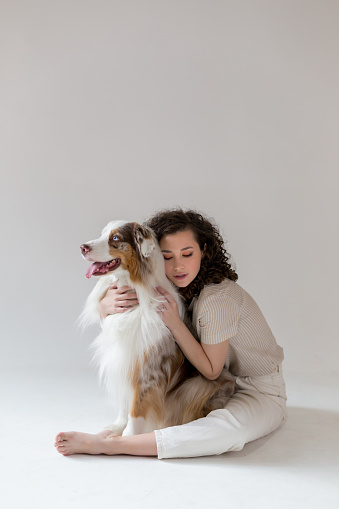 Beautiful woman and her dog posing together, Australian Shepherd Dog and young Curly woman, pets and leisure concept