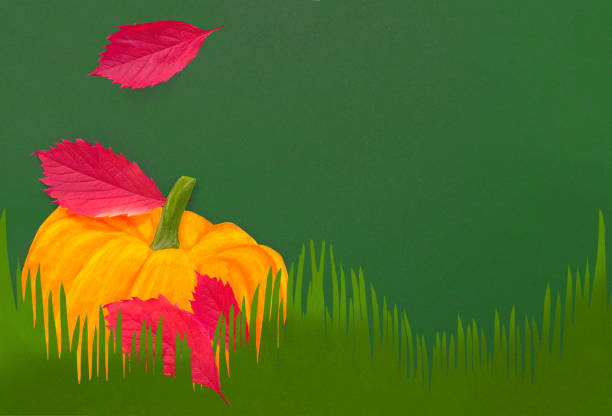 painted pumpkin on artificial green grass under real red leaves. autumn imitation
