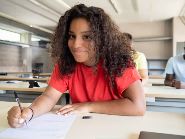 jovem afro-americana estudante olhando para a câmera enquanto fazia um exame - aluno do ensino médio - fotografias e filmes do acervo