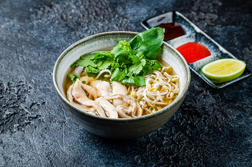 Vietnamese soup Pho GA with chicken and noodles on dark stone table